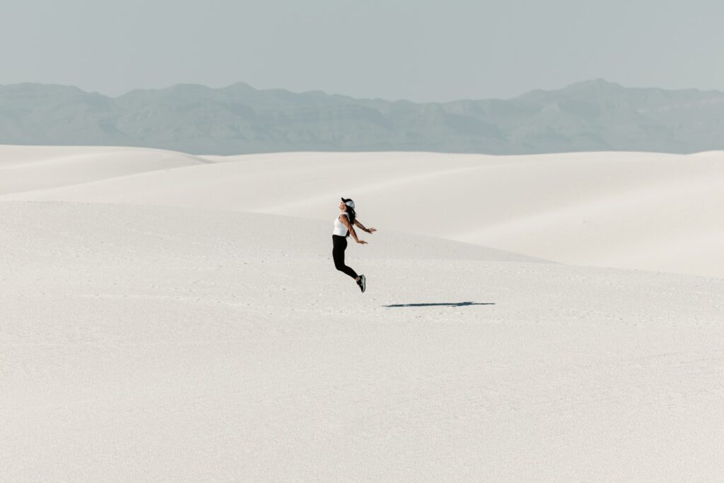 Woman jumping in vast white desert landscape