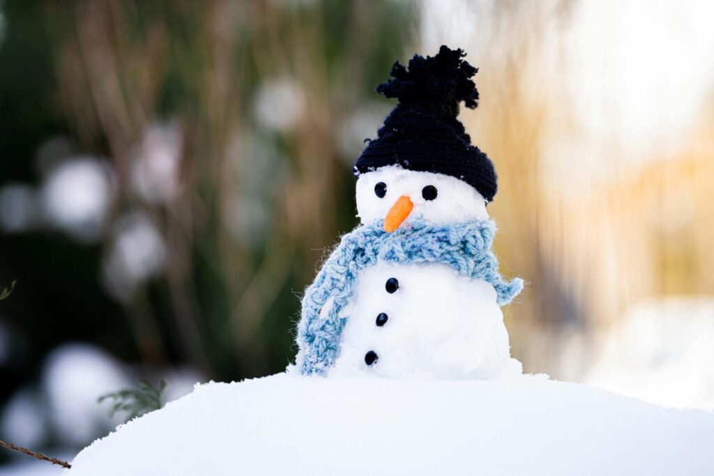 Cute snowman wearing a knitted hat and scarf, perfect for winter themes and decorations.